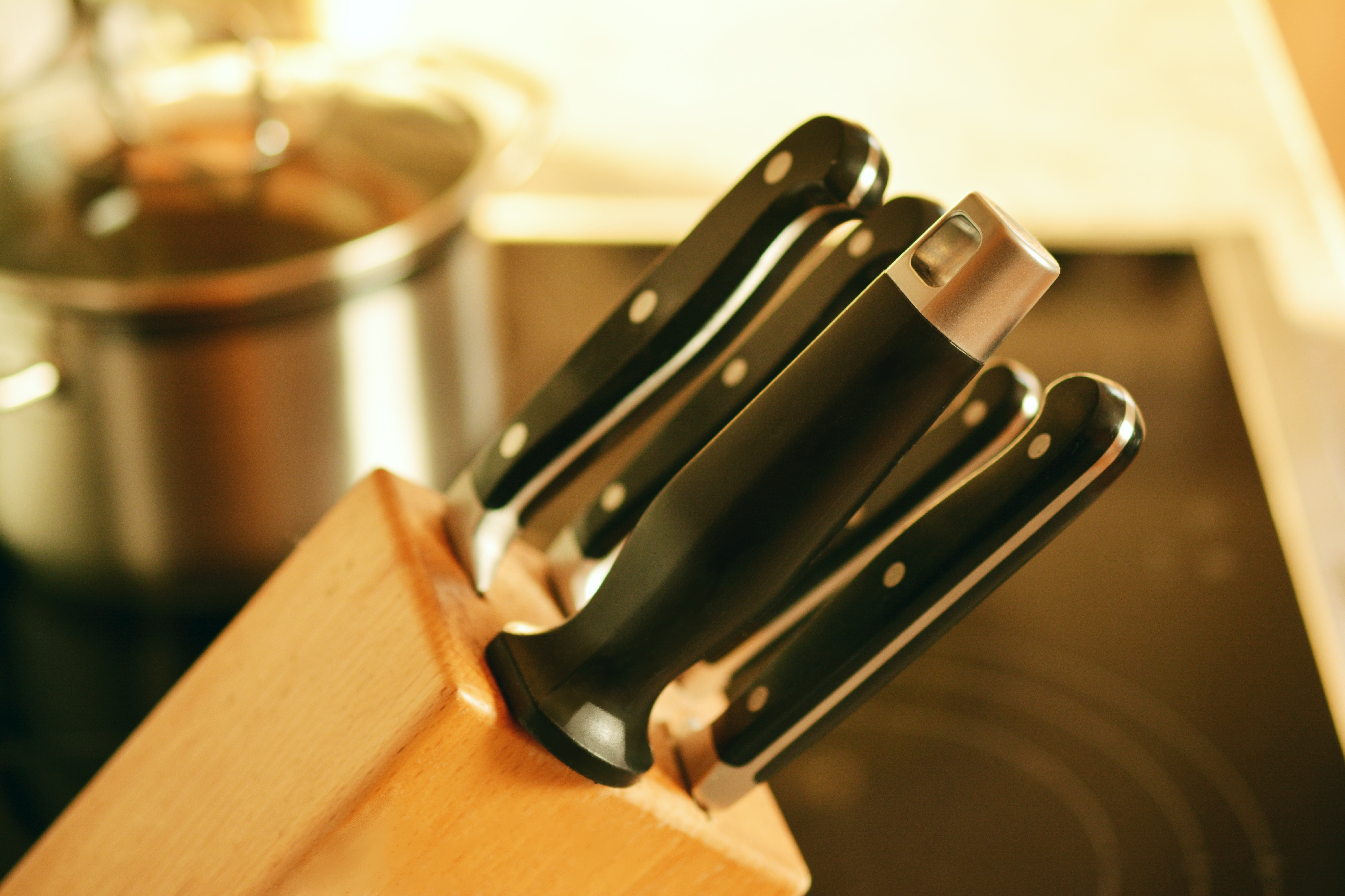 Image of knives in a butcher block, with stovetop nearby
