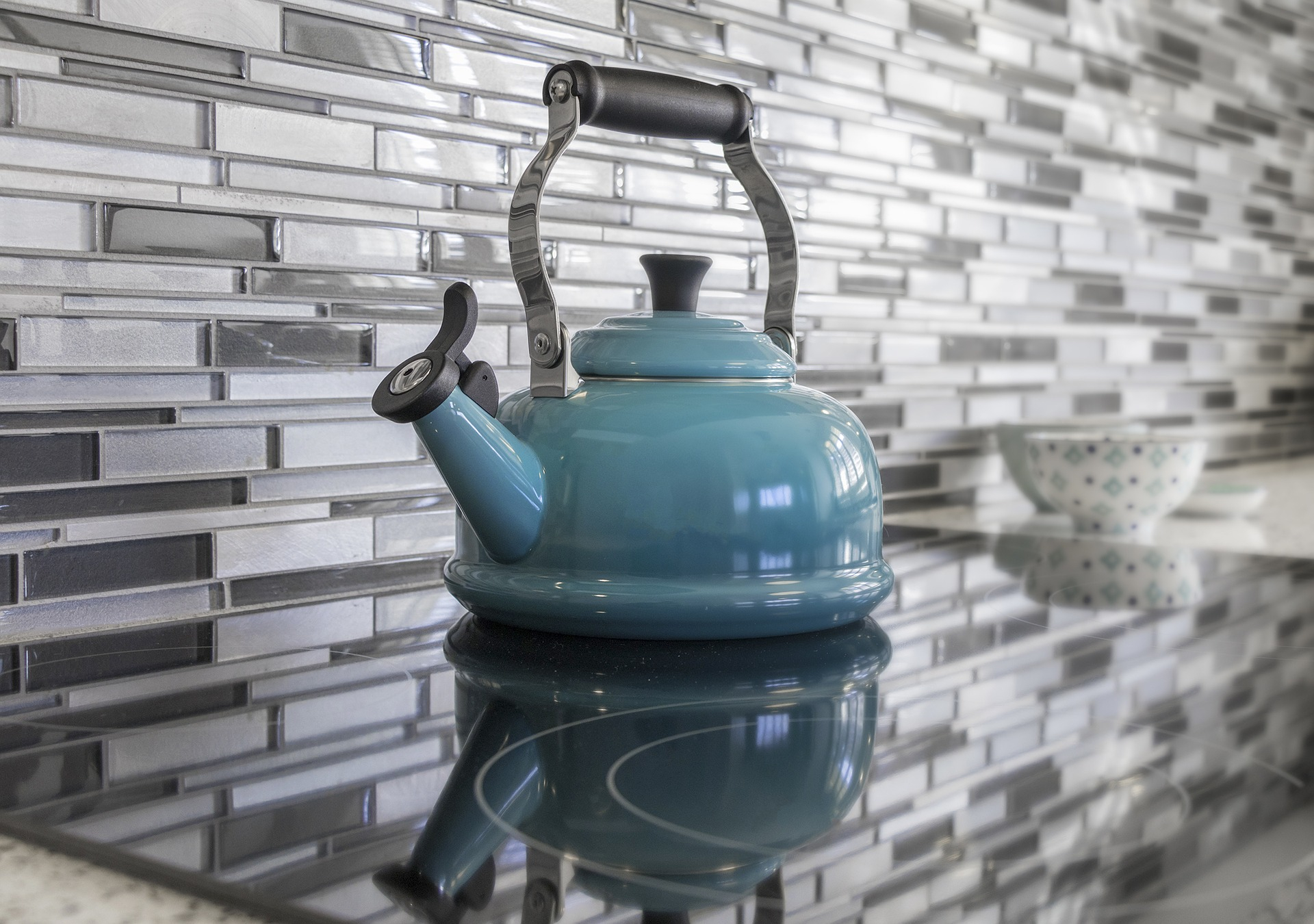 A kitchen stovetop with a blue tile backsplash
